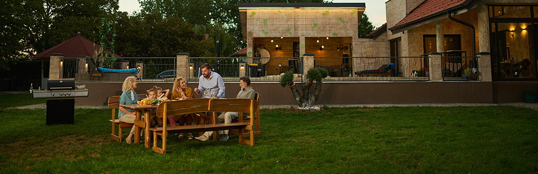 Family enjoying backyard barbecue dinner party at sunset
